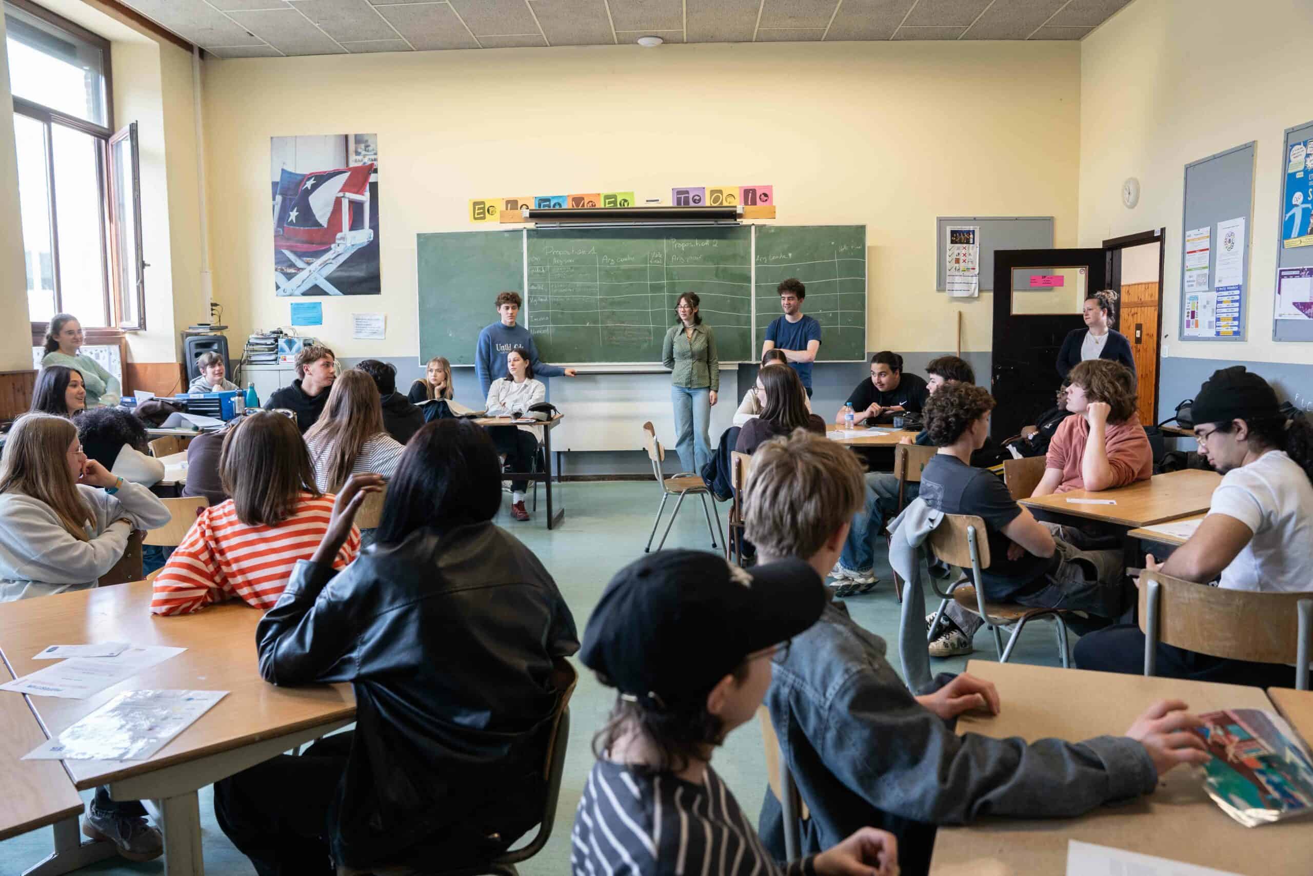 Une animatrice de Défi Belgique Afrique présente un atelier de citoyenneté mondiale et solidaire devant les élèves d'une école secondaire.